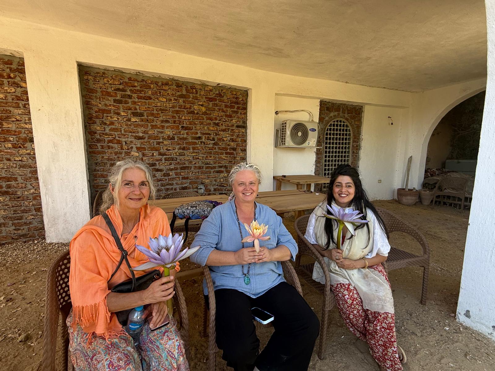 Three of the caretakers sitting together in the courtyard at Luxor, each holding a lotus