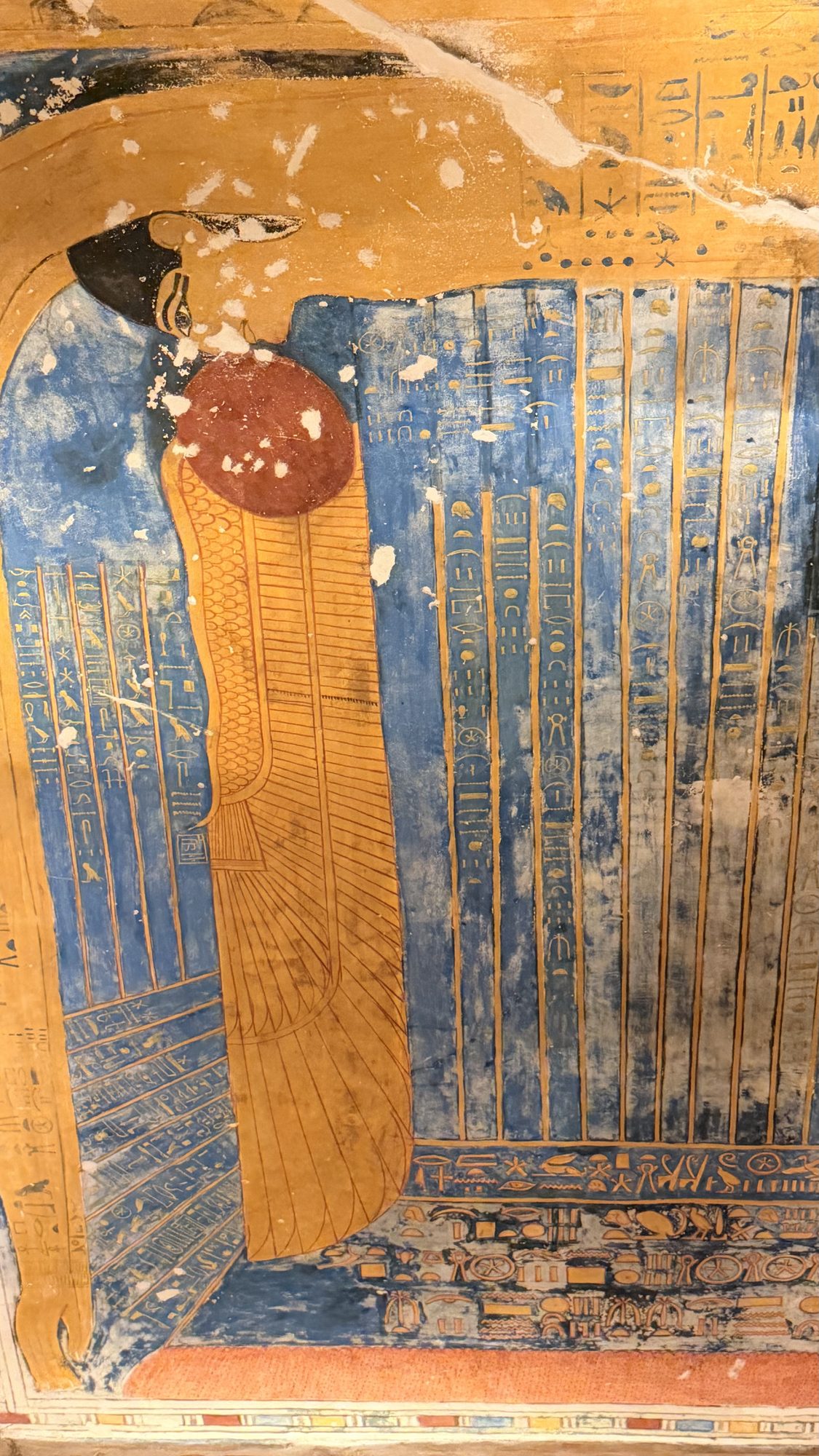 Painted temple ceiling showing Nut, the sky goddess, arched in blue and gold